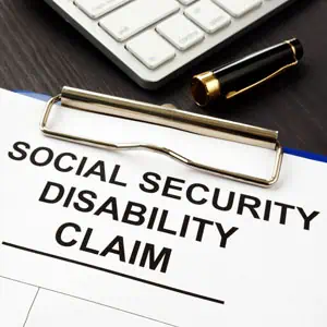 Social Security Disability Claim form on a clipboard, with a pen and calculator nearby.